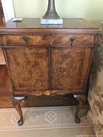 Front view of antique wooden side table showing two drawers with metal keyhole handles and double door cabinet below with matching handles and keyhole.
