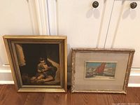 Front view of oil painting and sailboat print side by side on floor