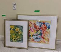 Both framed artworks shown together on floor, visible sizes and frames.