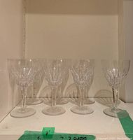 Seven Stuart Crystal wine glasses lined up on a white surface, showing overall size and pattern.