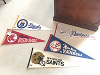 Group shot of five vintage felt pennants laid on light carpet under wooden furniture