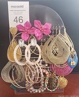 Wide view of assorted costume earrings hung on display stand showing variety of styles and materials