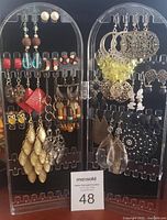 Full display of assorted costume earrings on two clear acrylic earring stands showing variety of styles, colors, and shapes.