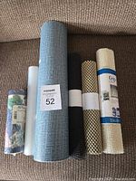 Six rolls including two wallpaper rolls and four liner grip rolls displayed on a couch.