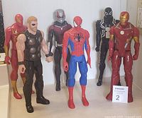 Group photo of six Marvel action figures: Iron Man (red/gold), Thor, War Machine, Spider-Man, Venom (black symbiote), Iron Man (black/white)