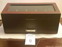 Closed wooden watch box with glass top, featuring silver drawer handle and smooth finish.