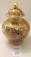 Side view of the vintage Chinese ceramic vase showing the detailed hand painted floral and geometric patterns with gold embellishments, and the removable lid topped with a gold knob.