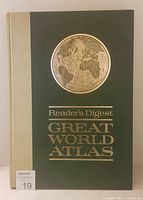 Front cover of the vintage Reader's Digest Great World Atlas showing green cover with gold embossed globe and text.