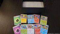 Top-down photo of spread Japanese Pokémon cards in front of black box filled with cards