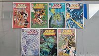 Top-down photo of all 7 Flash Gordon comics showing the front covers in two rows on a table, displaying colorful and dynamic cover art.