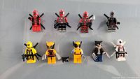 Photo showing a total of nine LEGO minifigures consisting of four Deadpool and five Wolverine characters with various costumes and accurate accessory details.