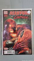 Front cover of Deadpool Vs Carnage #1 Marvel comic, showing characters Deadpool and Carnage in an intense close-up fight. Comic sealed in protective bag with backing board visible.