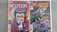 Two Wolverine #1 comics resting side by side in plastic sleeves, showing front covers.