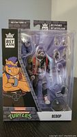 Front view of BST AXN Bebop action figure in packaging showing figure and accessories.
