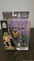 Front view of Donatello Ninja Turtles BST AXN action figure in packaging with accessories visible