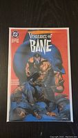 Photo of comic book cover showing 'Vengeance of Bane #1' with Bane character illustrated prominently.