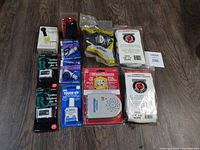 Photo showing 11 assorted new home maintenance and repair items including electrical testers, connectors, rope, and water alarm.