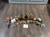 Photo showing all 24 assorted figurines arranged in two rows on a wood floor.