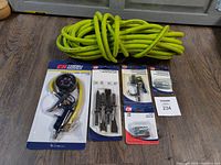 Complete lot showing yellow Husky air hose coiled and tied, Campbell Hausfeld tire inflator with gauge in retail packaging, multiple air tool accessories and fittings in packaging including air chisels and adapters