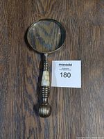 Magnifying glass with round lens and decorative handle lying on wooden surface photographed from above.
