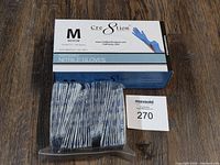 Box of Cre8tion brand medium disposable nitrile gloves with pack of assorted adhesive bandaids on wood surface