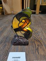 Front angled view showing the illuminated stained glass butterfly wings on a floral bronze base.