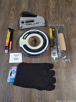 Lot of tools and supplies including stapler, drywall tape, gloves, trowel in package