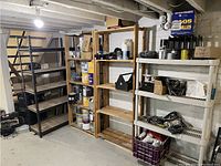 Wide view of four distinct shelving units: metal adjustable shelf, two wooden shelves, and one plastic shelf. Various cans and cords are placed on shelves.