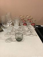 Straight on view of all glassware showing various shapes and styles including Stella Artois glasses, etched crystal glasses and a small smoky glass votive holder.