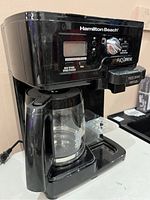 Front view of Hamilton Beach FlexBrew coffee maker showing control panel, carafe, and single serve brew station.