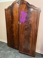 Pair of tall solid walnut doors with arched tops and rich wood grain finish.