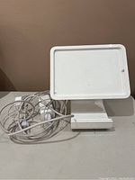 Front view of white Square stand designed to hold an iPad with built-in card reader at the base and attached power cable.