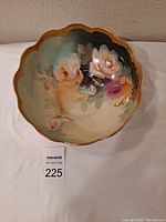 Top view of porcelain bowl showing hand-painted rose design with gold trim around scalloped edges.