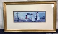 Front view of the framed coastal scene print showing the gold wood frame and white mat around the elongated image depicting women walking by the sea.