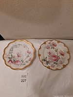 Top view of two decorated floral Haviland Limoges porcelain plates showing scalloped edges and gold rims