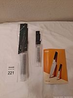 Two kitchen knives, one large and one smaller, wrapped in protective plastic alongside a product brochure titled Filet by Bespoke Post.