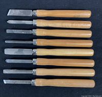 Top view showing all eight lathe chisels and gougers with wooden handles and various blade shapes.