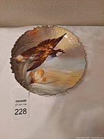 Front view of hand painted Limoges porcelain plate showing bird in flight and scalloped edges.