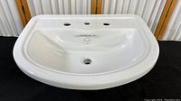 Porcher white porcelain countertop sink with rounded edges and integrated backsplash with three faucet holes and one central drain hole, placed against vertical wooden and metal panels.
