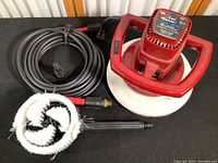 Red WEN Orbital Car Waxer with attached white foam pad, black washer hose coiled beside it along with a black and white circular brush accessory.