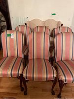 Front view showing six upholstered dining chairs with striped fabric and wood claw feet, arranged in two rows.