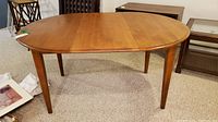 Ethan Allen oval dining table without leaf attached, showing wood surface and tapered legs.