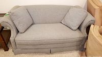 Front view of Ethan Allen gray cloth loveseat with two cushions on carpeted floor.