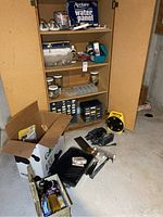 Wide view of the cabinet and area showing tools and hardware items both inside and on floor