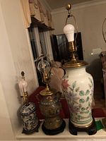 Three table lamps on a red sofa, showing different sizes and designs, no lampshades present.