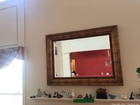 Full view of the mirror mounted on the wall with decorative items below it to show size and style.