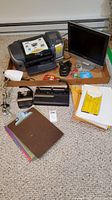 Full lot viewed from above, includes Samsung monitor, Epson printer, hole punchers, clipboards, paper, desk lamp, tape, and miscellaneous small office supplies.