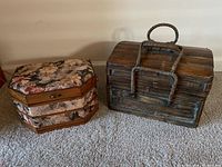 Two sewing baskets: one floral upholstered wooden box and one brown woven basket with handle.