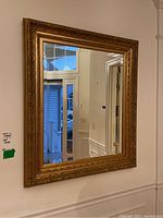 Full view of the gold framed wall mirror mounted on a wall.