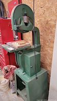 Front view of green band saw showing overall structure, cast iron base and table